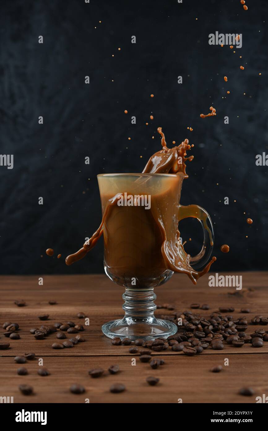 Splashing of coffee in glass cup on dark background Stock Photo - Alamy