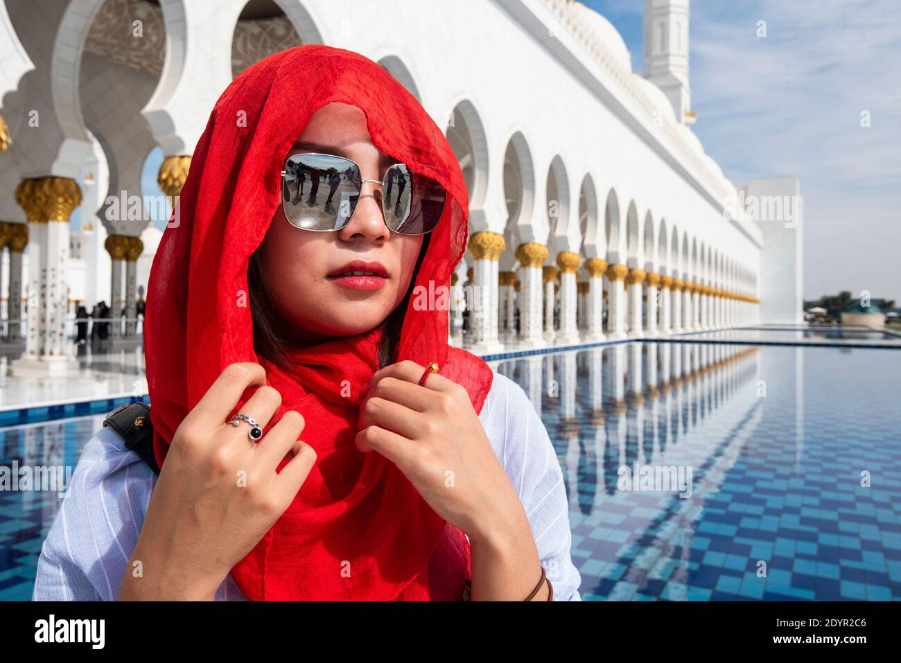 Chinese Tourist wearing red headscarf visits Sheikh Zayhed Grand Mosque Stock Photo