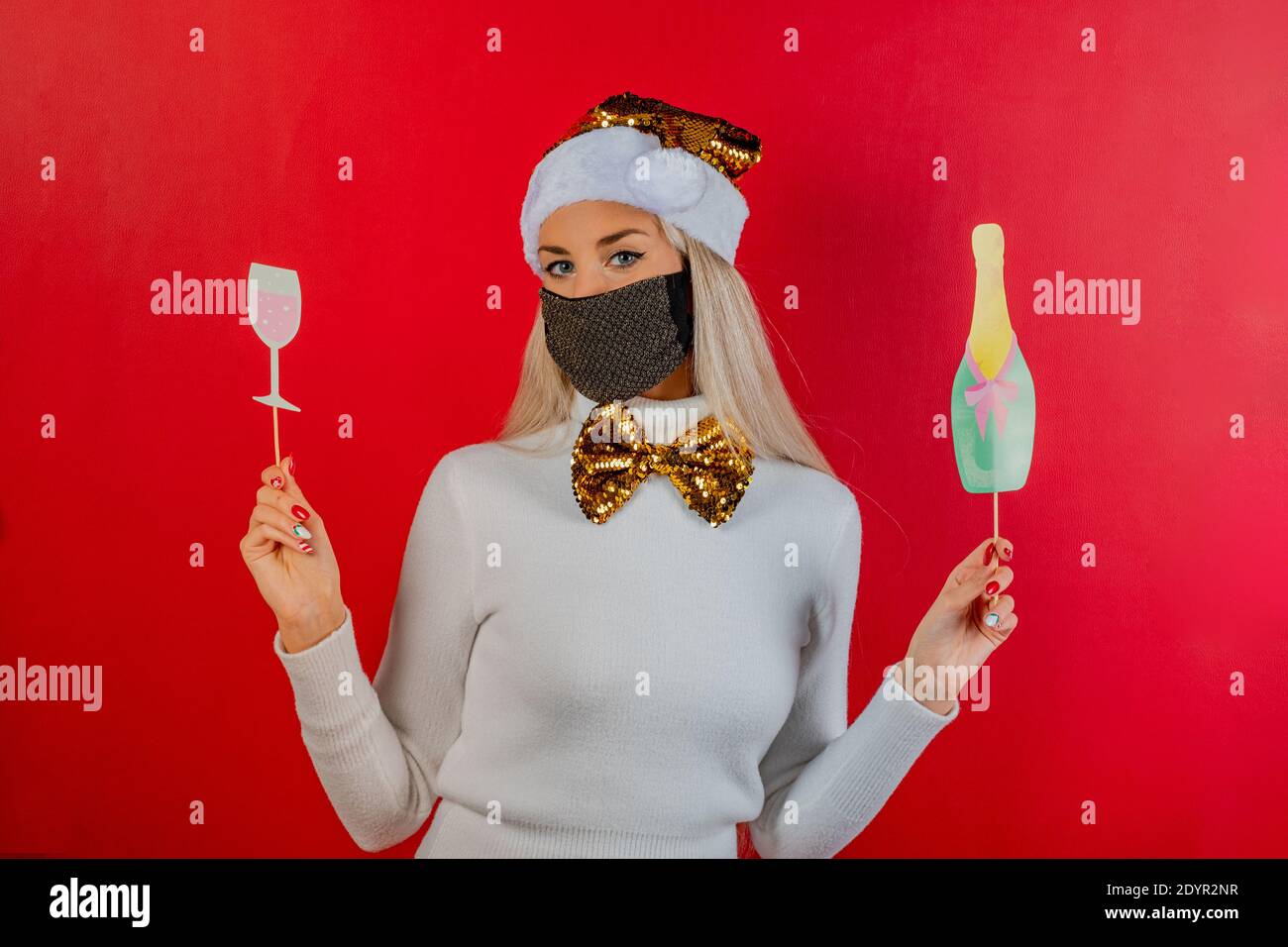 Woman in protective face mask holding a bottle and glass with hand. Party image in pandemic period. Playful young girl celebrating and toast Stock Photo