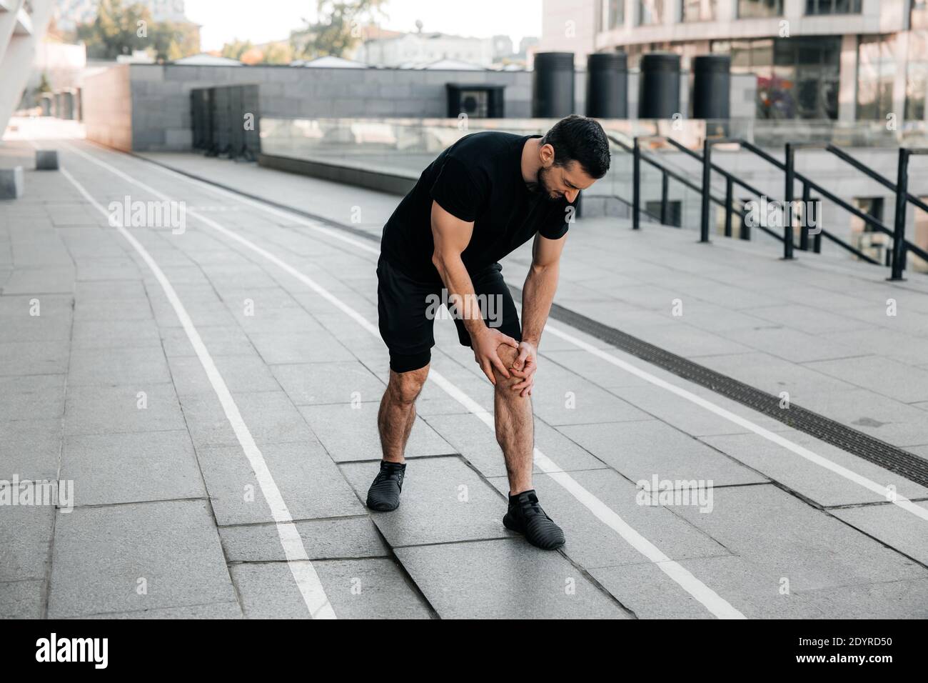 Attractive man feeling pain in his foot during sport workout outdoors
