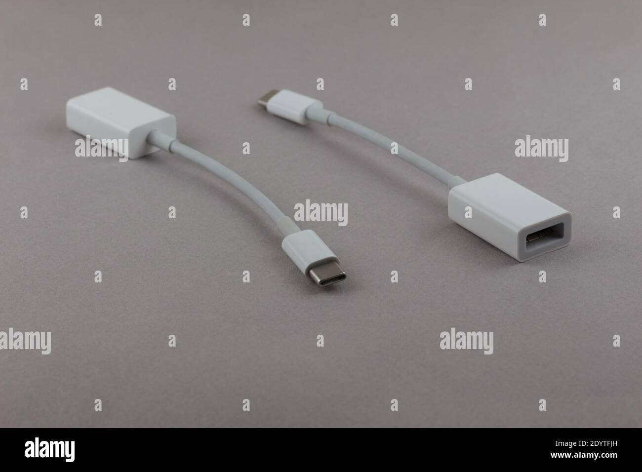 two white USB-C to USB adapters showing both ends, for connecting devices with USB cables to devices with USB-C ports, on a gray background Stock Photo