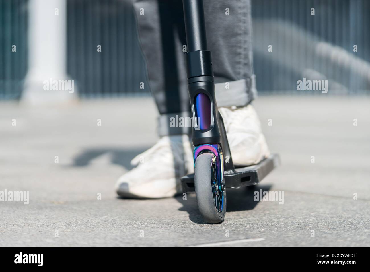young teenager in sneaker on modern extreme stunt kick scooter in skatepark Stock Photo