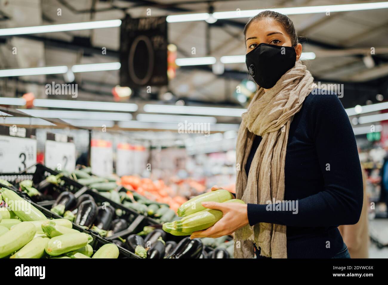 Young woman wearing protective face mask shopping in a supermarket,buying organic produce.Eating healthy food during coronavirus COVID - 19 pandemic.H Stock Photo