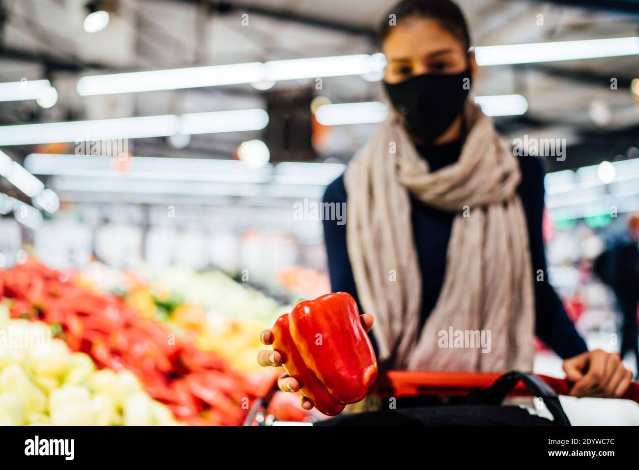 Young woman wearing protective face mask shopping in a supermarket,buying organic produce and ingredients.Eating healthy food during coronavirus COVID Stock Photo