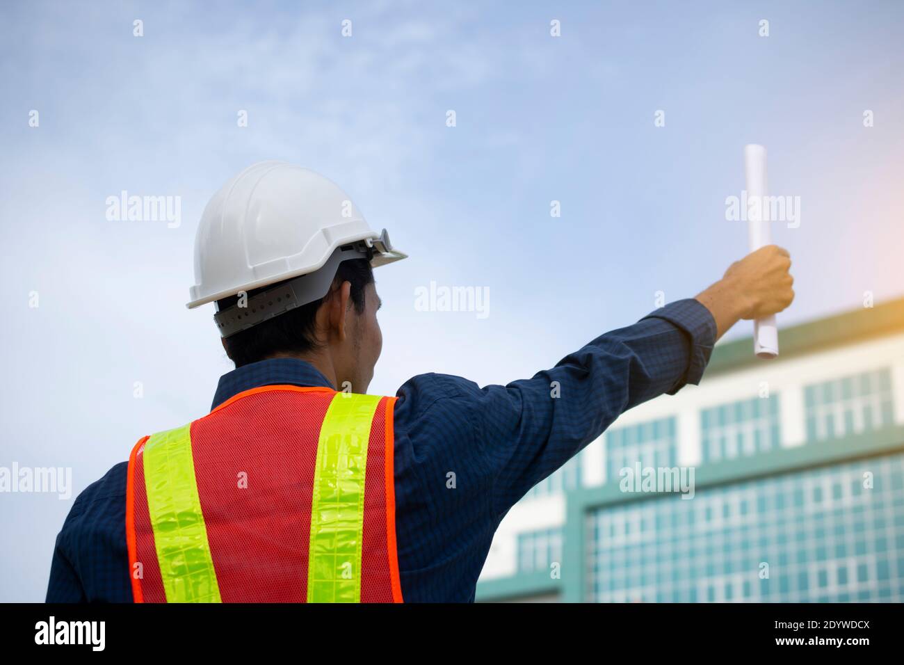 Engineer holding paper plan against building sky background Stock Photo ...