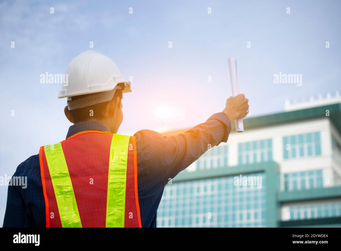 Engineer holding paper plan against building sky background Stock Photo ...