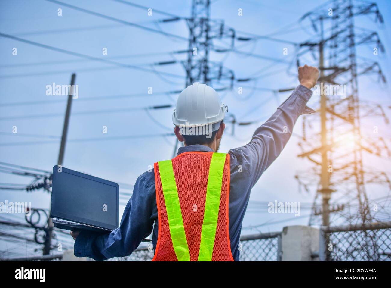 Engineer holding computer notebook high voltage power plant background Stock Photo