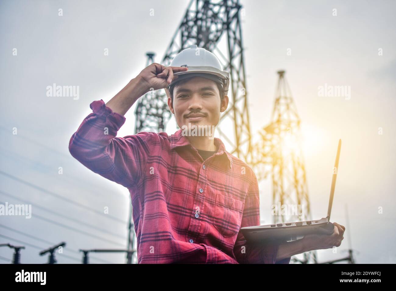 Engineer holding computer notebook high voltage power plant background Stock Photo