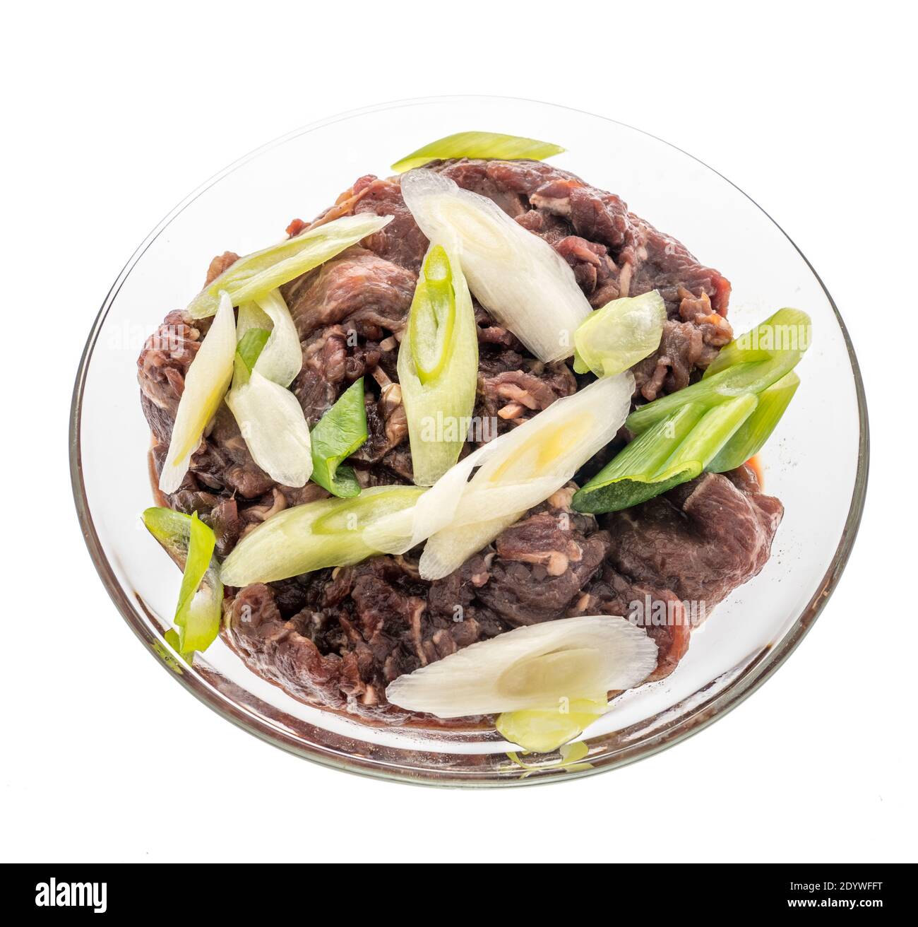 Beef Bulgogi with green onion inside a glass bowl a South Korean meal on an isolated background Stock Photo