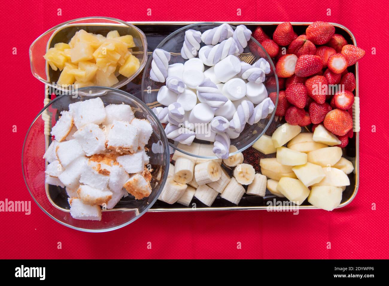 Assorted food for fondue including dessert of strawberries, apples, banana, angel food cake pineapple and marshmallows Stock Photo