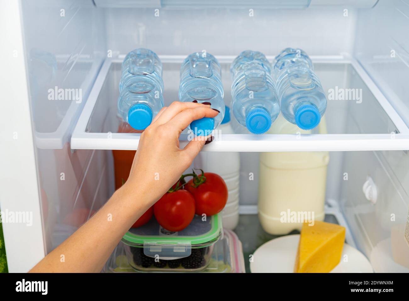Female hand taking bottle of water from a fridge Stock Photo Alamy