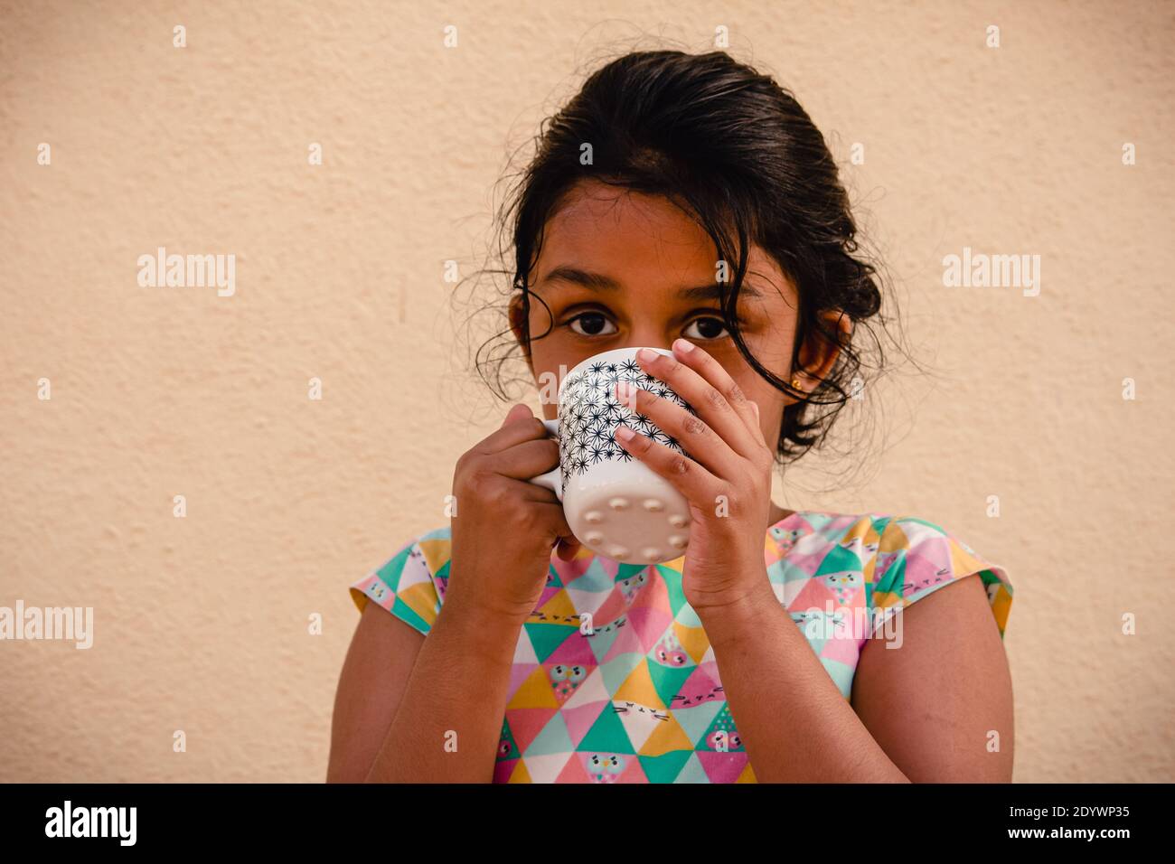 A young and school going kid enjoying and drinking her hot milk in a mug Stock Photo
