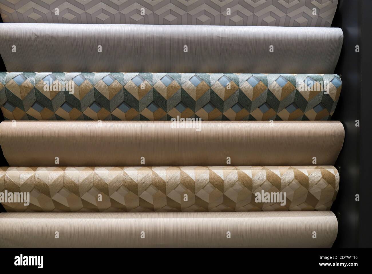 Rolled up rolls of vinyl wallpaper. Different textures and colors, as background. Green, beige, gray wallpaper with three dimensional pattern Stock Photo
