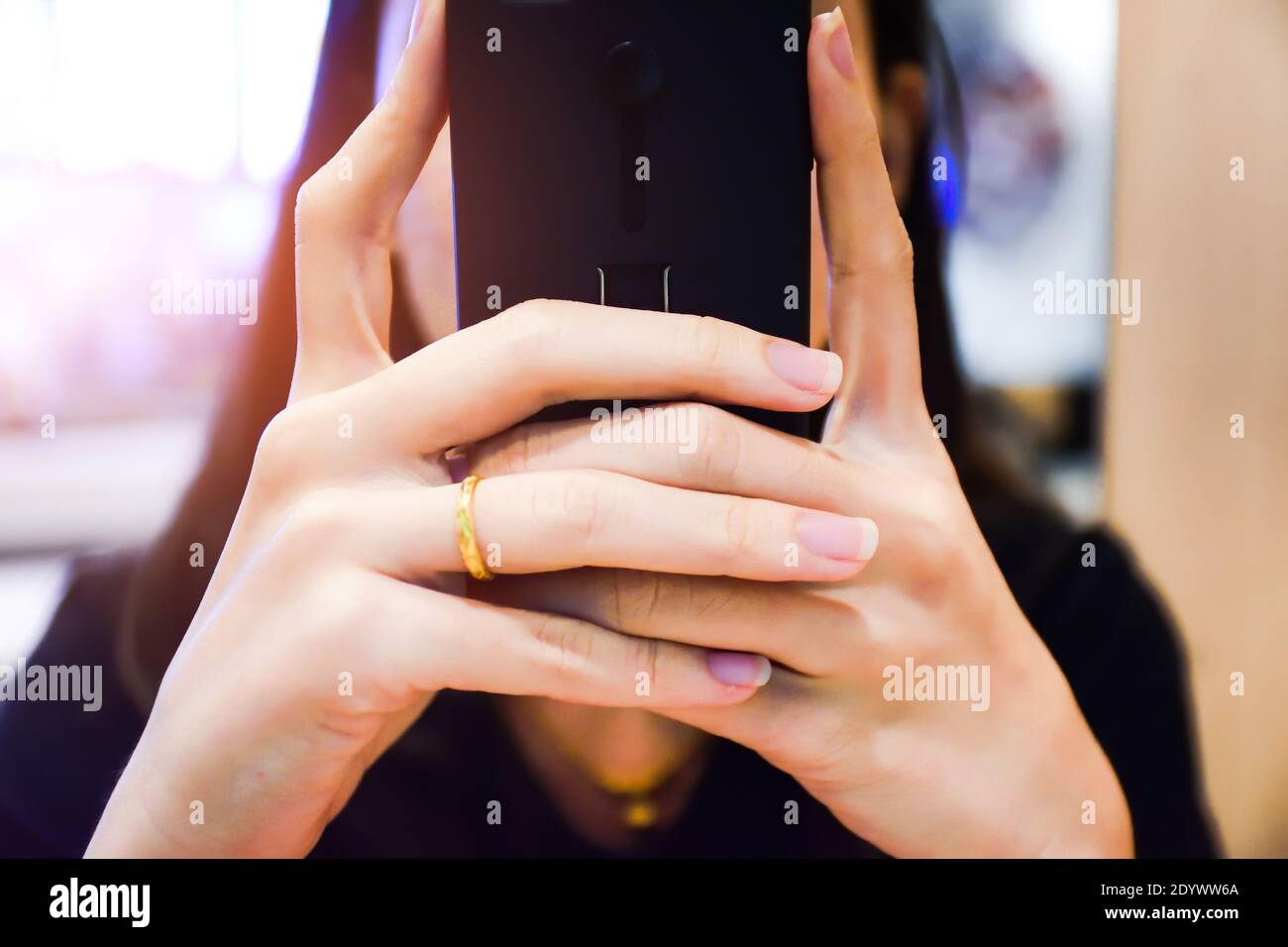 women holding smart phone on hand and seating against sunlight