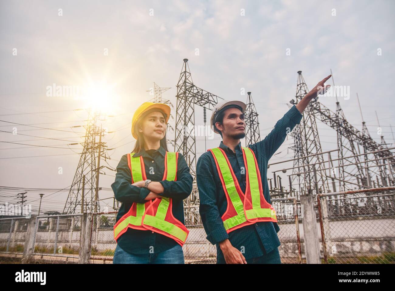 Two Electrician Engineer high voltage tower background Stock Photo