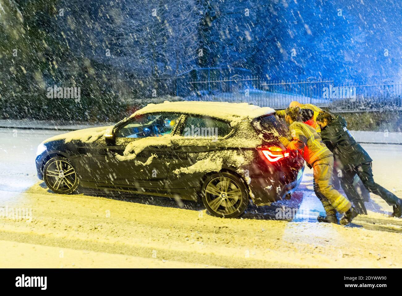 Cradley Heath, West Midlands, UK. 28th Dec, 2020. A fire crew pushes a stranded paramedic's car up a snowy hill this morning, as she tries to make it into work for her day's shift. Snow settles and causes traffic delays in Cradley Heath in the West Midlands Credit: Peter Lopeman/Alamy Live News Stock Photo