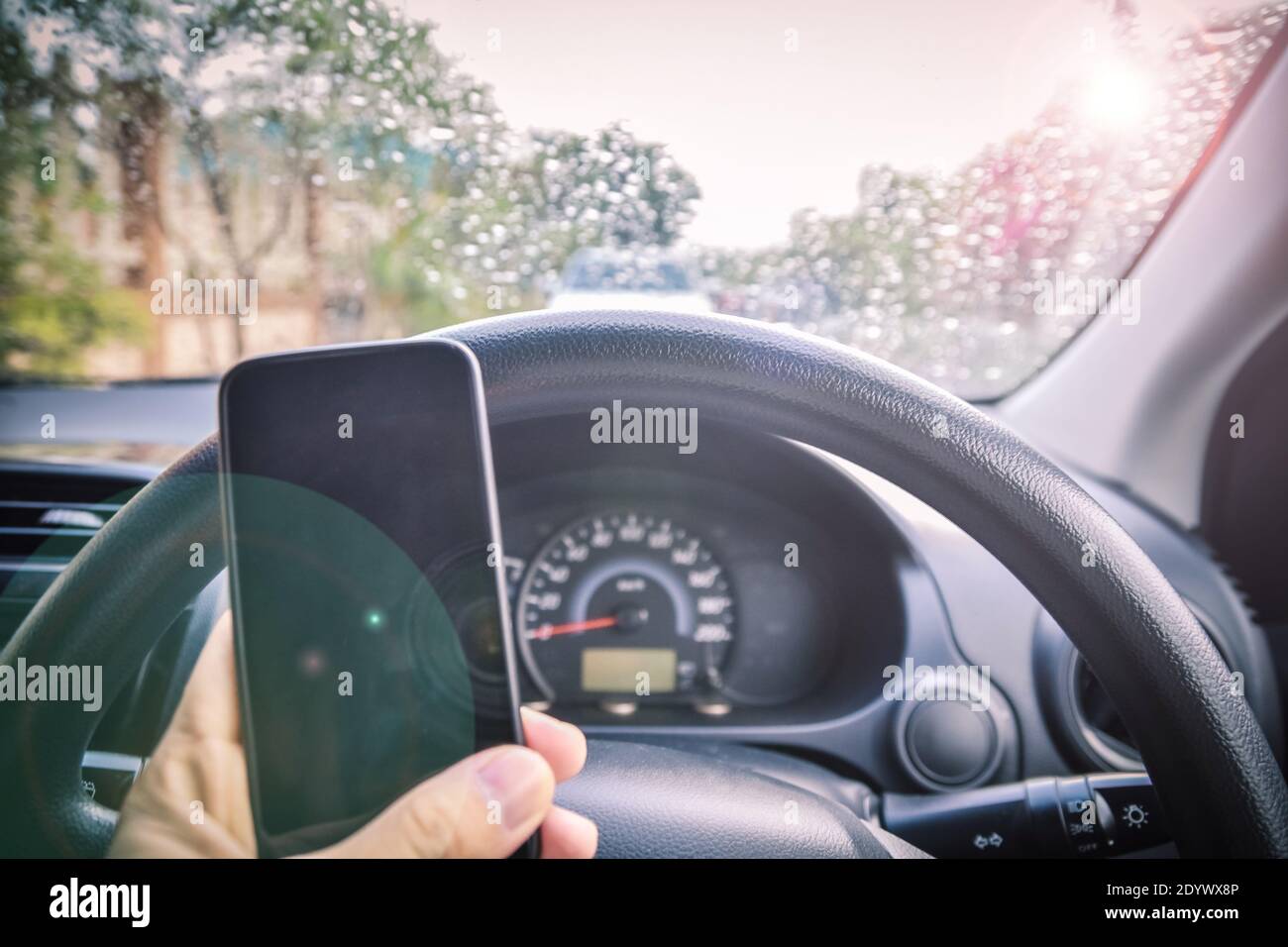 Car parked on street on morning and rain drop,hand holding phone in car