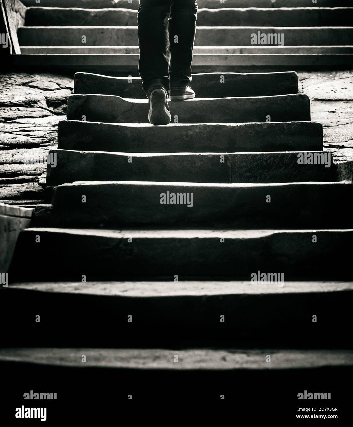 concept: a person is going away by the stairs to the outside, image in monochrome tones Stock Photo