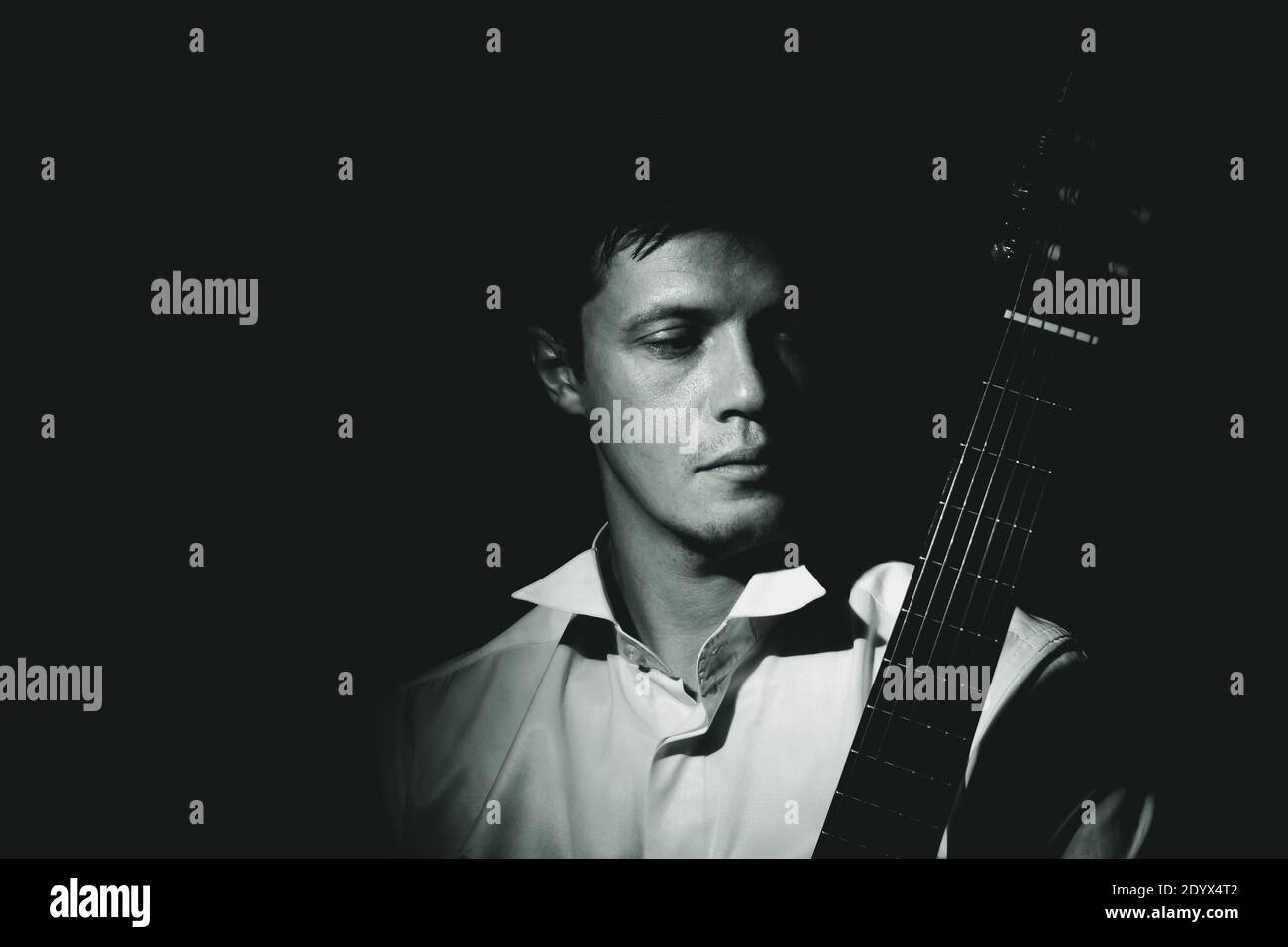 Young man with classic guitar. Black and white dramatic portrait, low key. Stock Photo