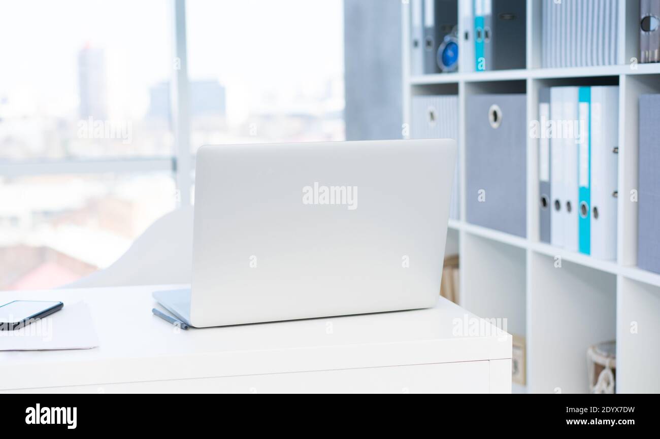 Modern laptop on white table in light office Stock Photo
