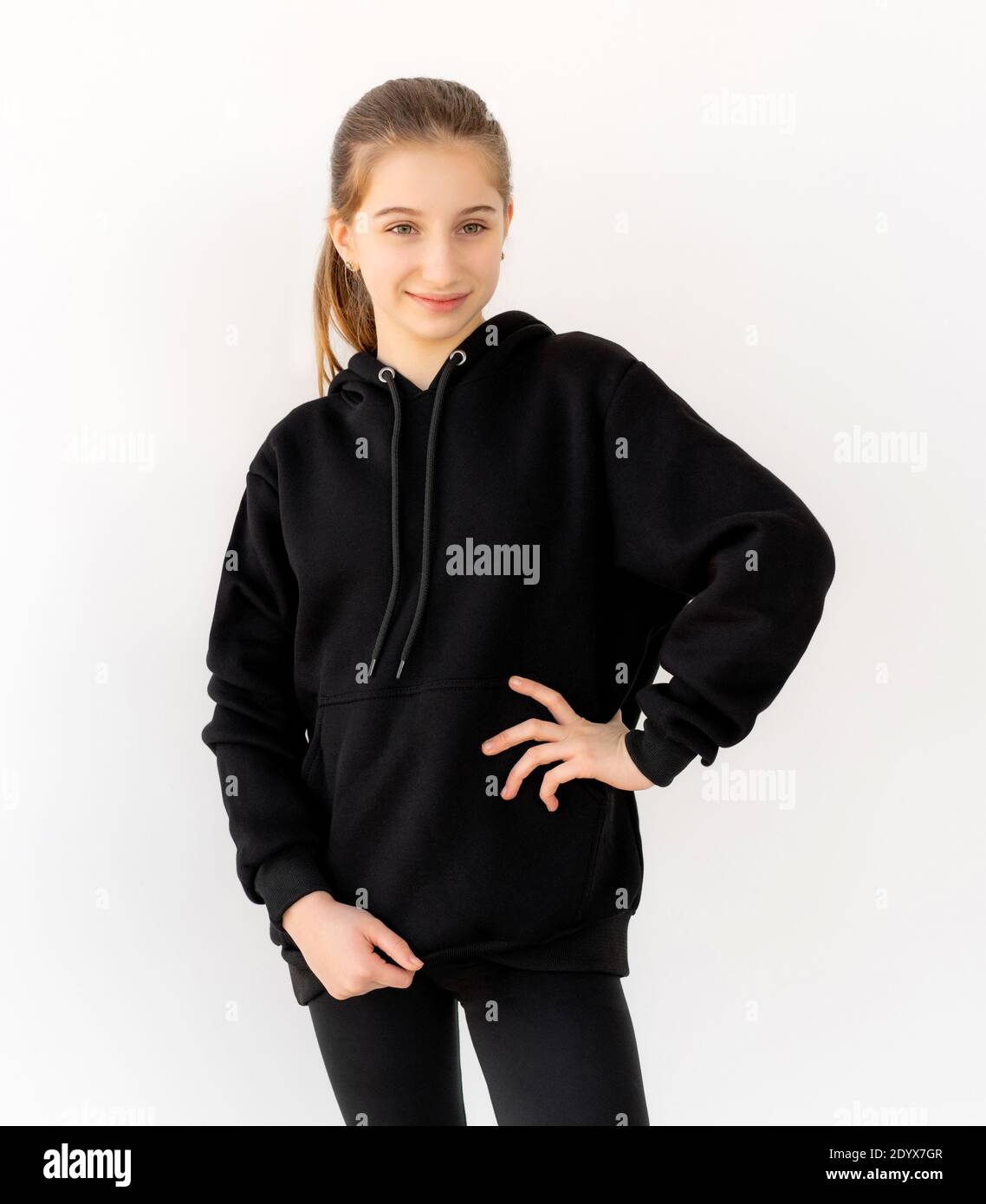 Attractive teenage girl posing in black hoodie isolated on white
