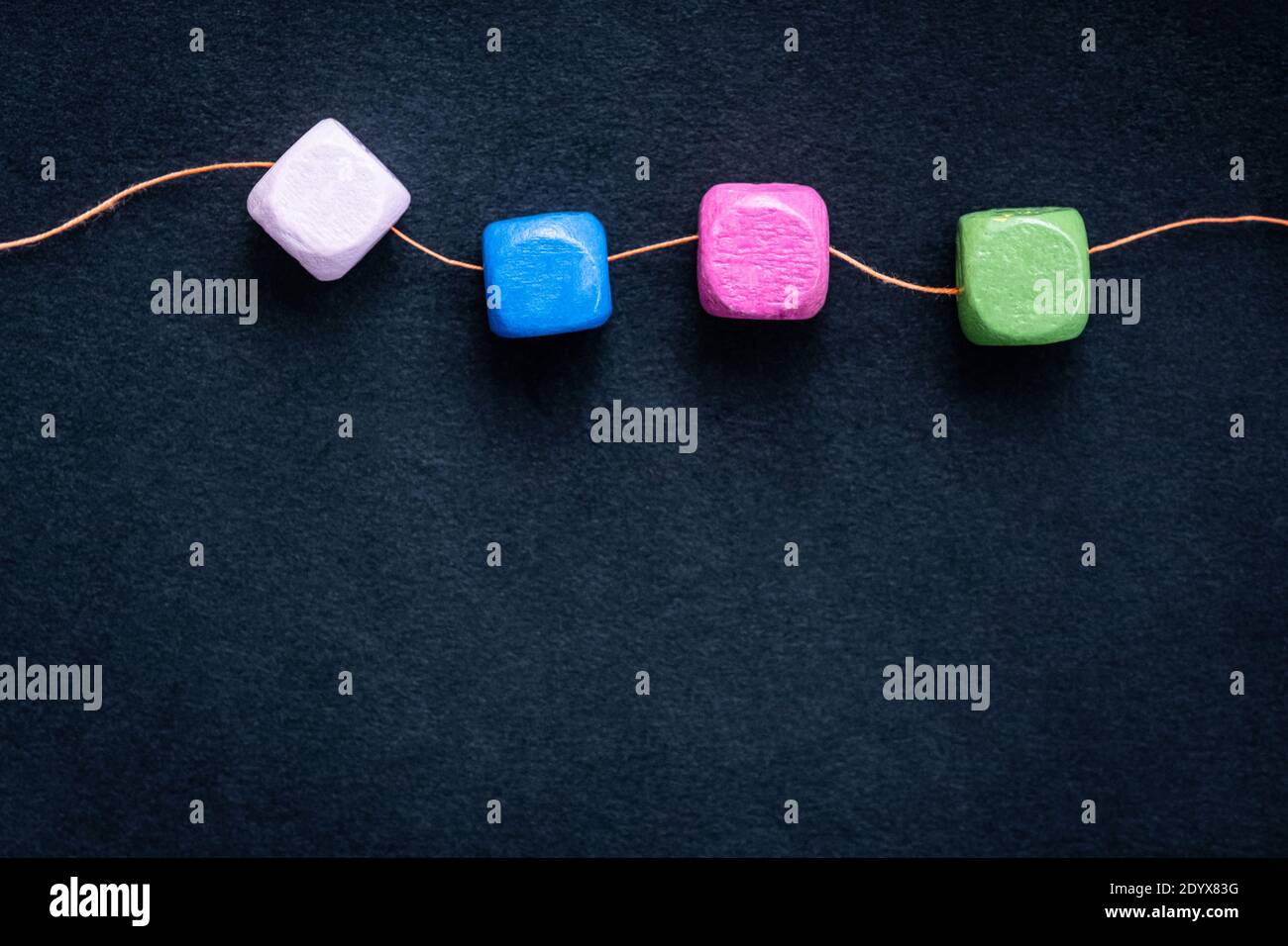 Bright wooden cube beads on thread macro with copy space Stock Photo