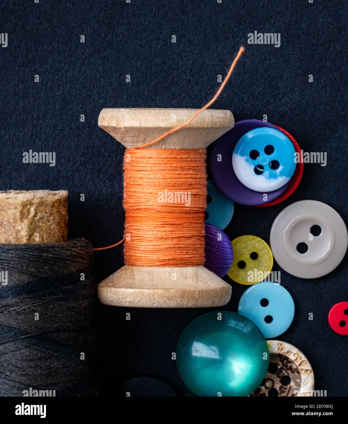 Colorful sewing buttons and orange thread spool macro Stock Photo