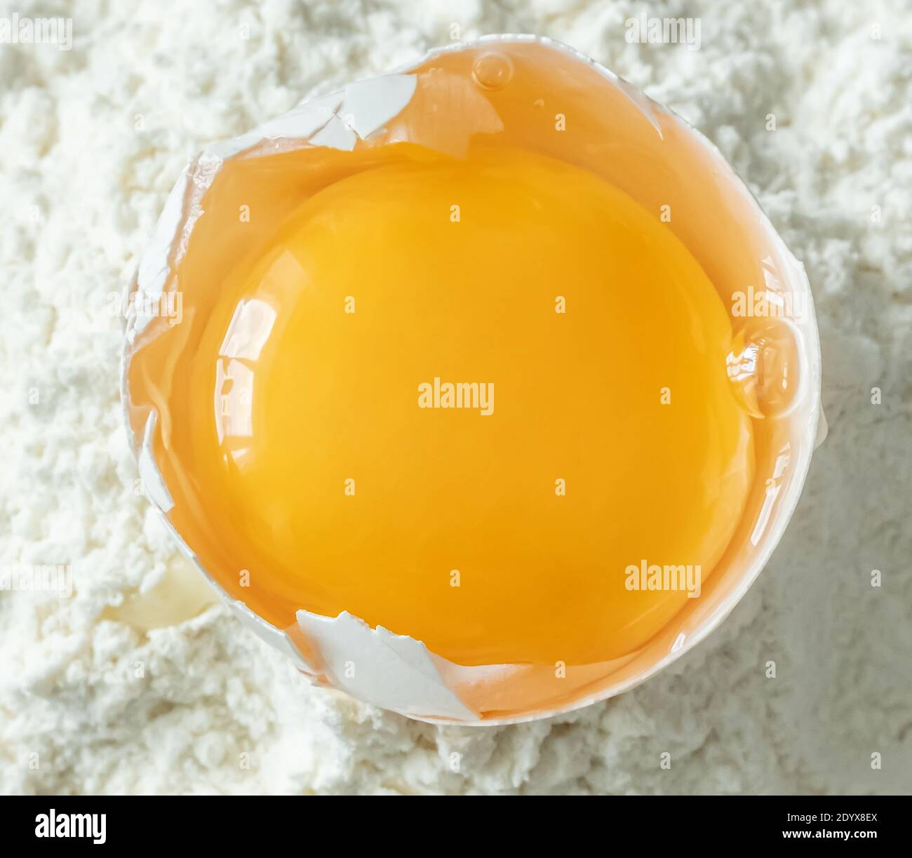 White egg and egg yolk on flour background, close up Stock Photo