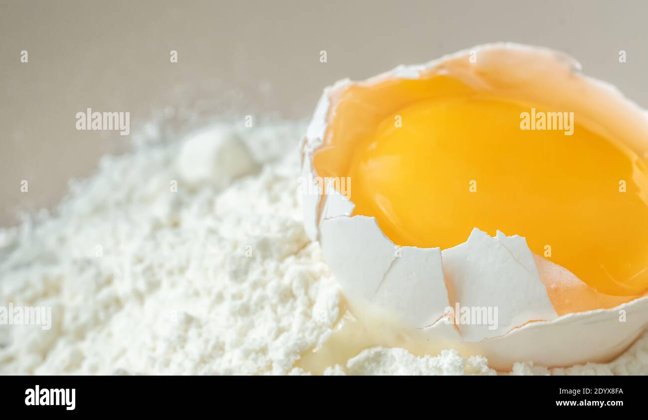 Cracked chicken egg with yolk on white flour Stock Photo