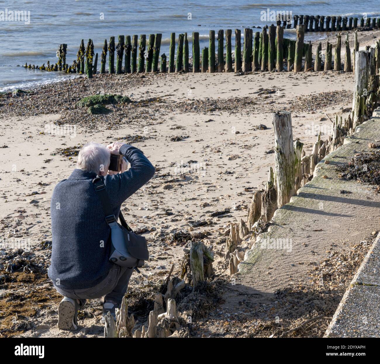 Male photographer taking a photograph at Lepe Beach, New Forest, Hampshire, England, UK Stock Photo