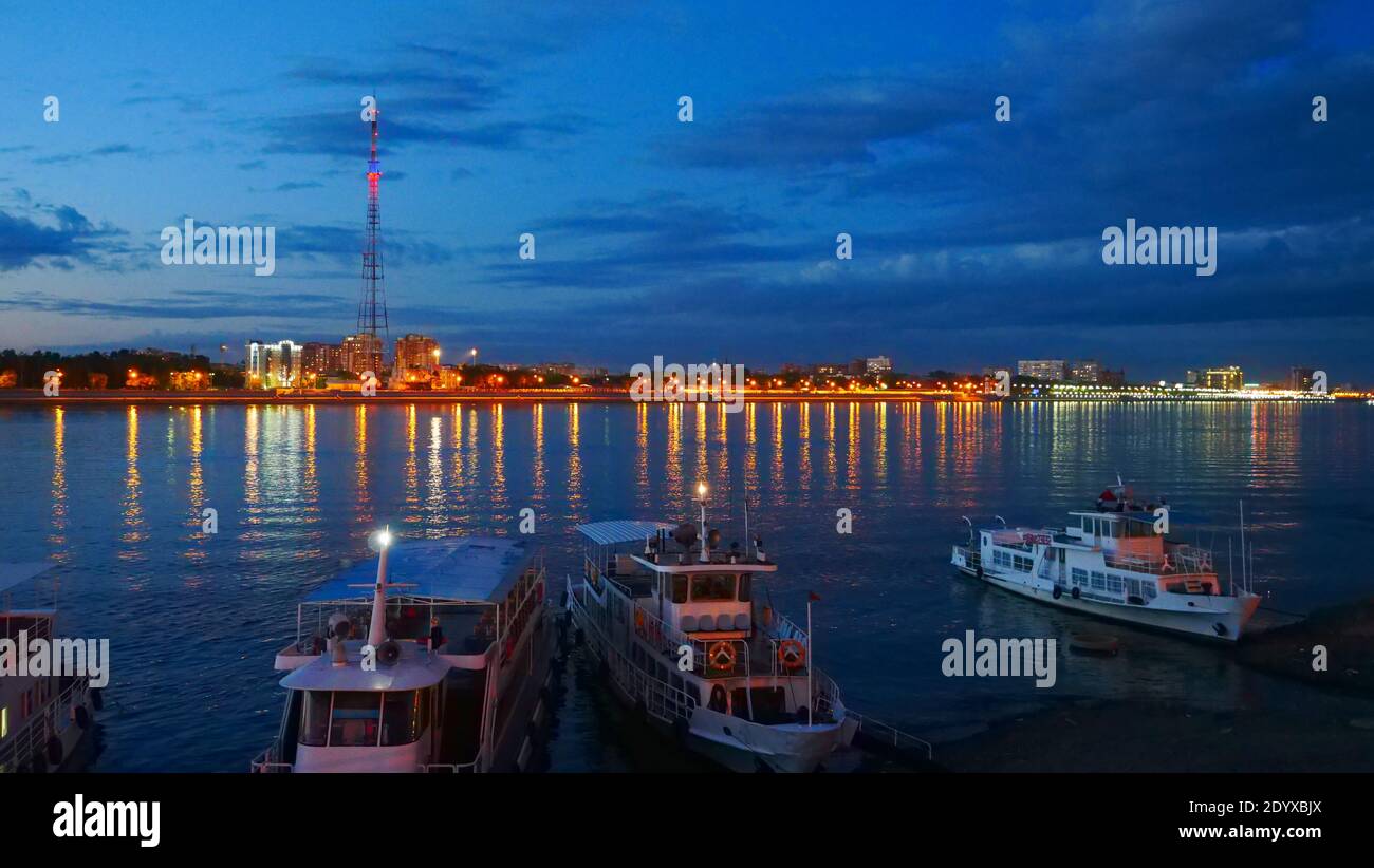 City skyline during nighttime: City lights and ships decorated with lights Stock Photo