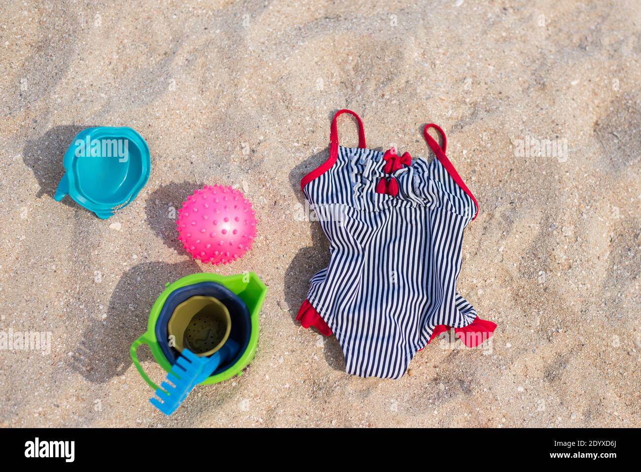 Beach accessories for kids on the sand flat lay. swimsuit and toys. Top
