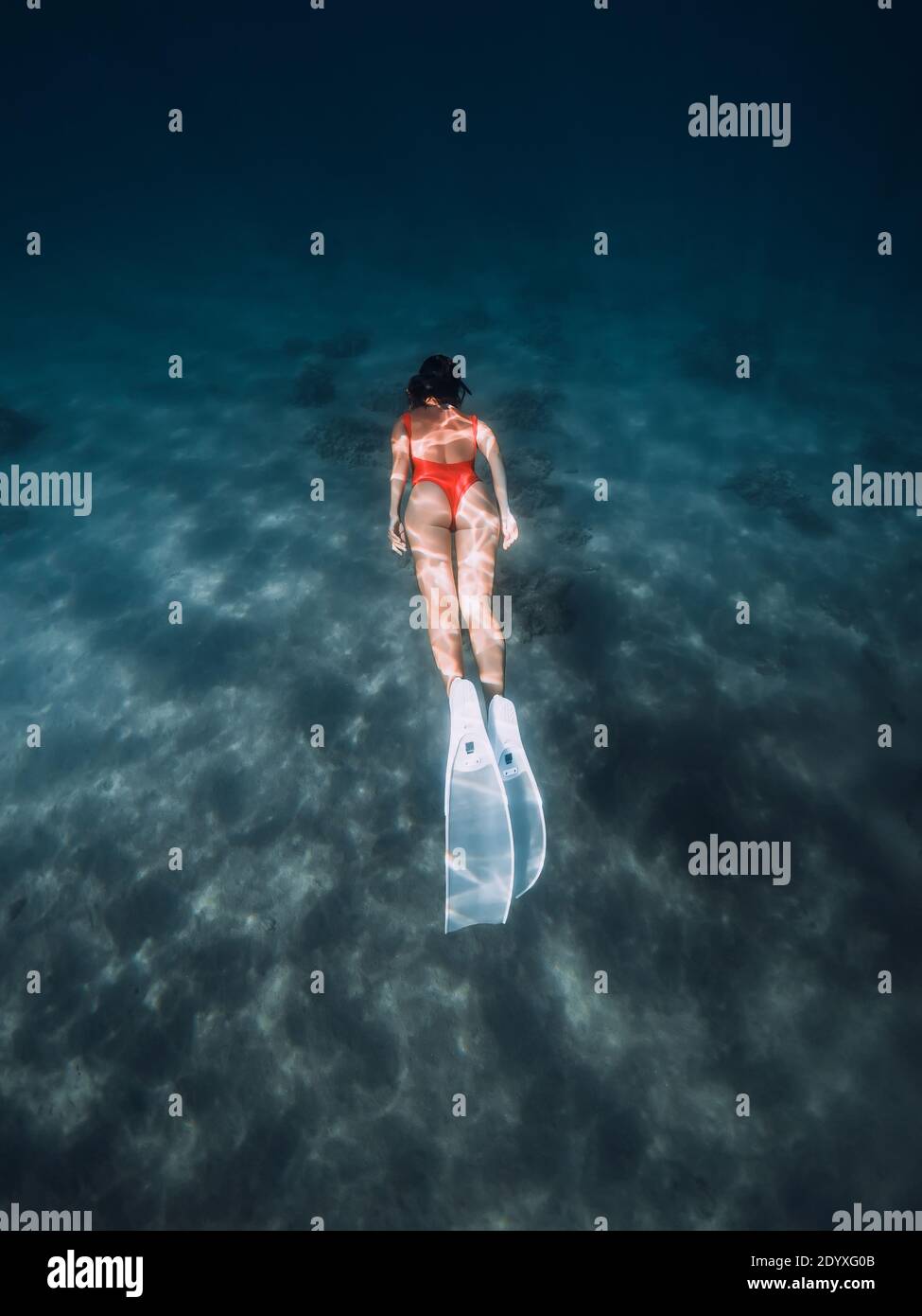 Freediver woman dive underwater with white fins. Summer freediving with