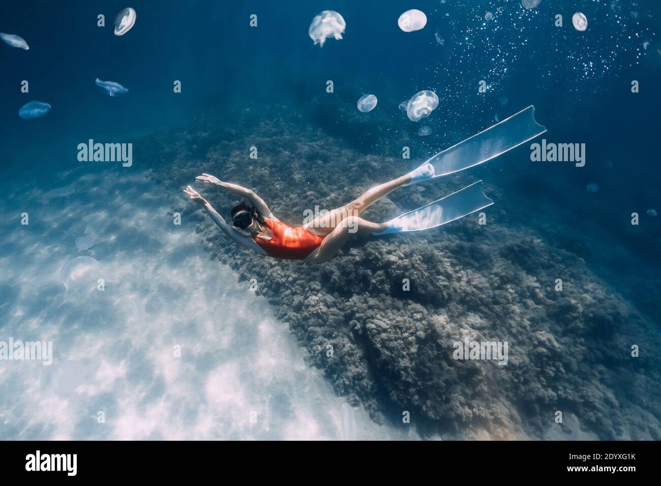 Woman freediver with white fins and jellyfish underwater. Freediving