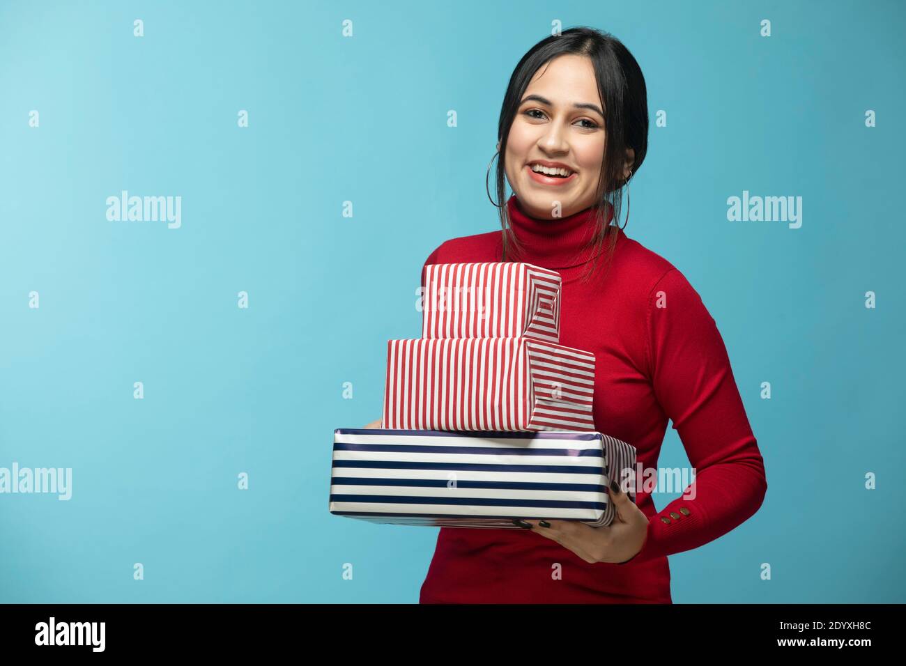 Portrait of young woman wearing red sweatshirt and holding gift box in hand Stock Photo