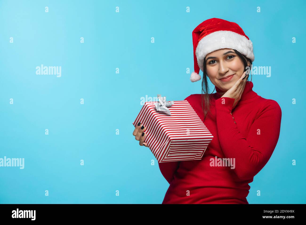 Portrait of Smiling young woman wearing Christmas hat and holding gift box Stock Photo