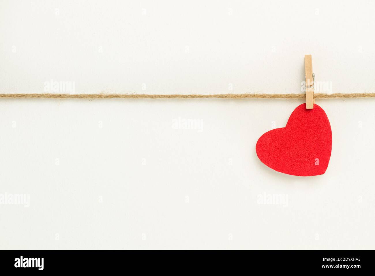 A red paper heart hanging from a sisal yarn on white background Stock ...