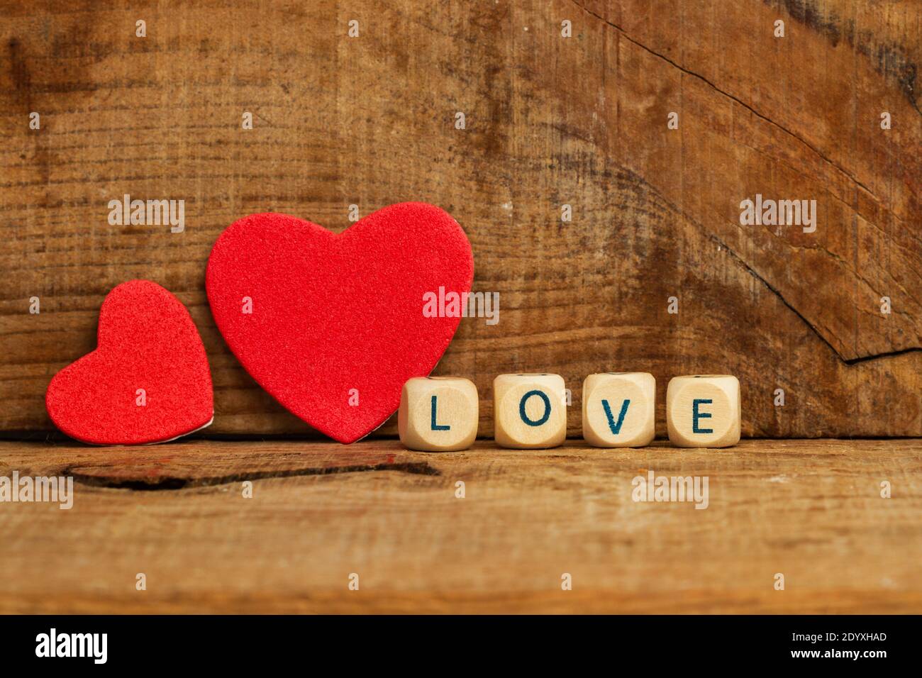 Two red paper hearts on a wooden background with a love sign Stock Photo