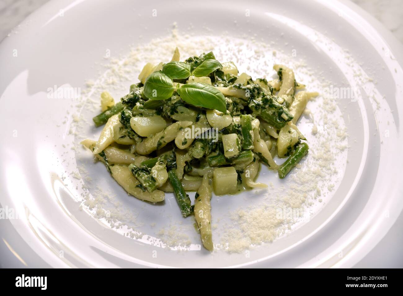 Trofie al pesto - Italian pasta with basil pesto sauce, potatoes and green beans  typical of Genoa, Liguria, Italy - close up in white dish with grate Stock Photo