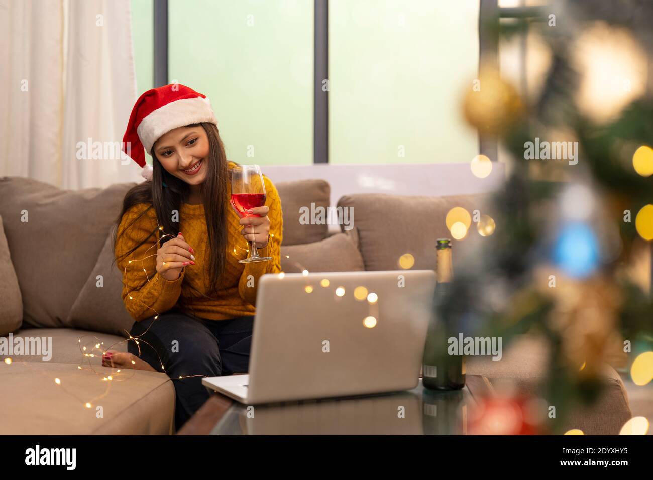 Happy Woman Making Video Call During Christmas Celebration holding wine glass Stock Photo