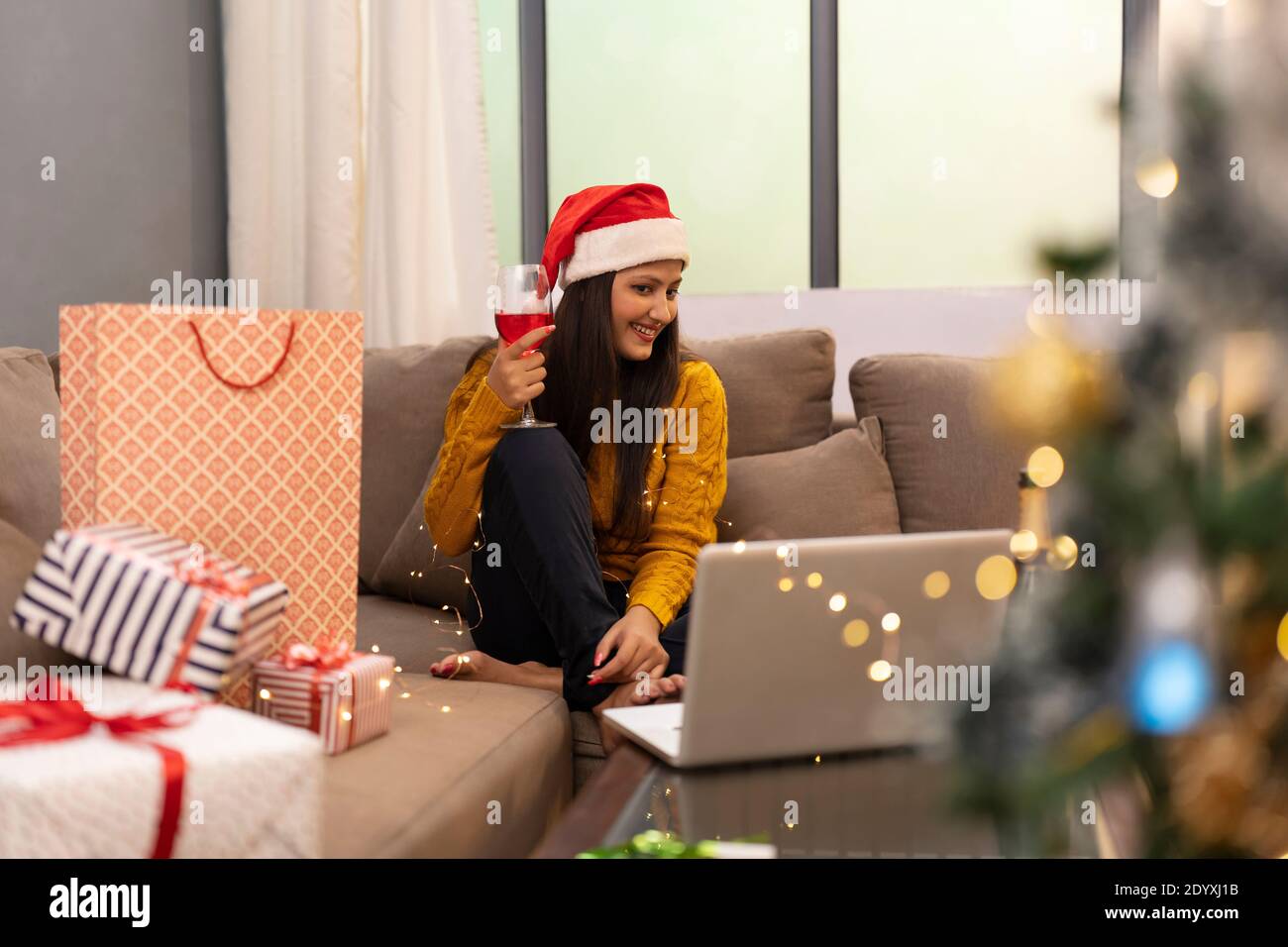 Happy Woman Making Video Call During Christmas Celebration holding wine glass Stock Photo