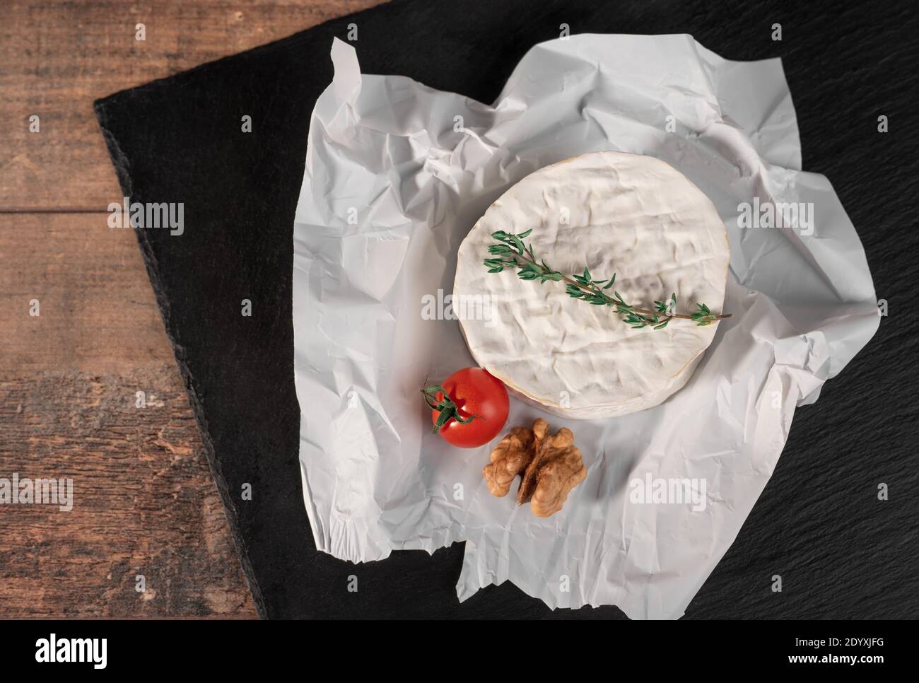 Delicious brie cheese on black background. Brie type of cheese. Camembert. Fresh Brie cheese and a slice on stone board. Italian, French cheese. Stock Photo