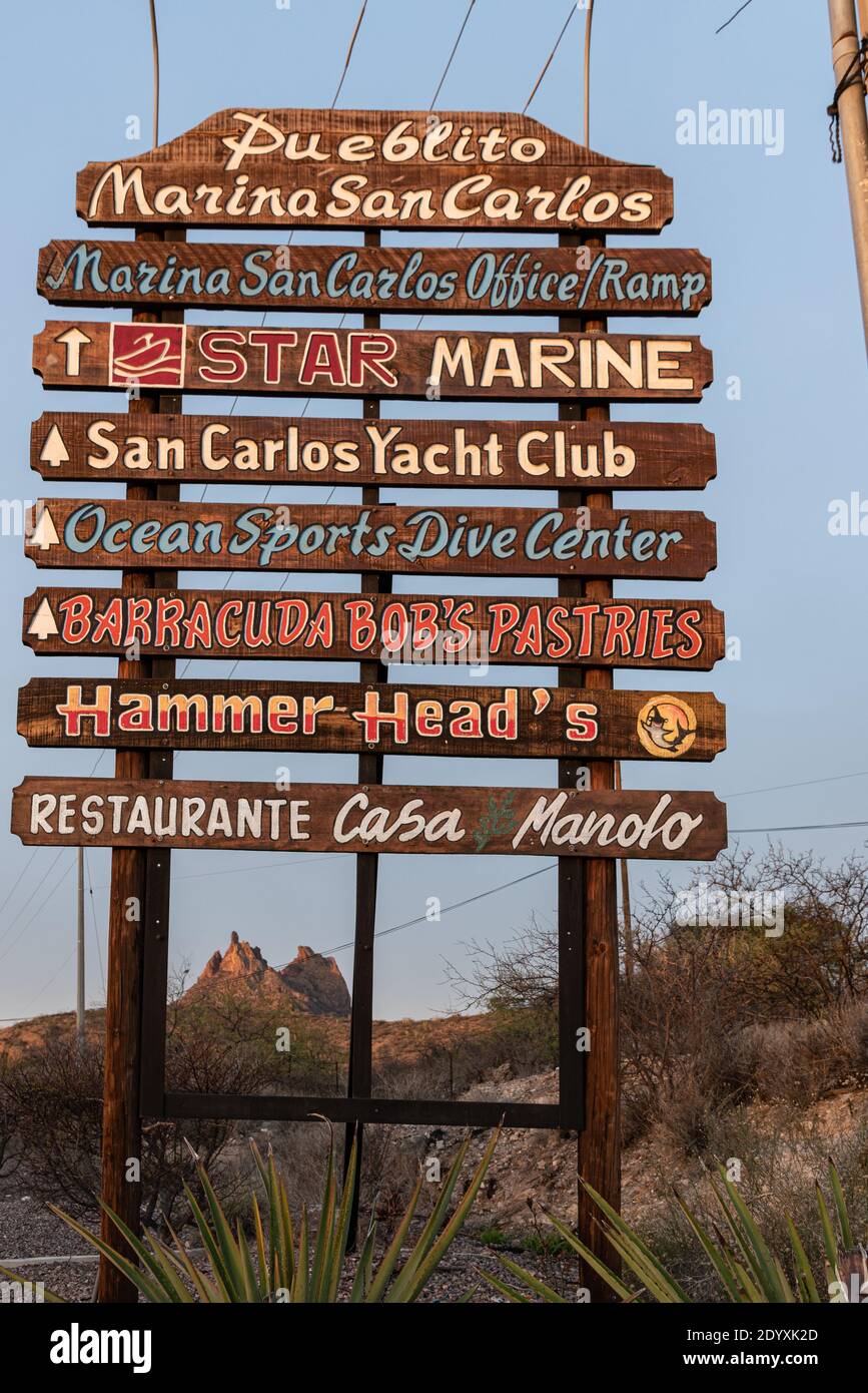 A wooden hand-painted sign advertises businesses in Marina San Carlos in San Carlos, Sonora, Mexico. Stock Photo