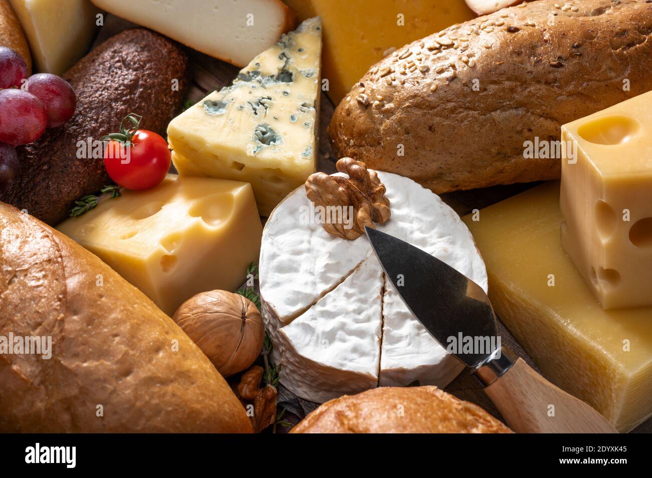 cheese and bread background. many types of bread and cheese. cheese platter, tasting assortment of various types of cheese, grape, walnut, tomato. fro Stock Photo