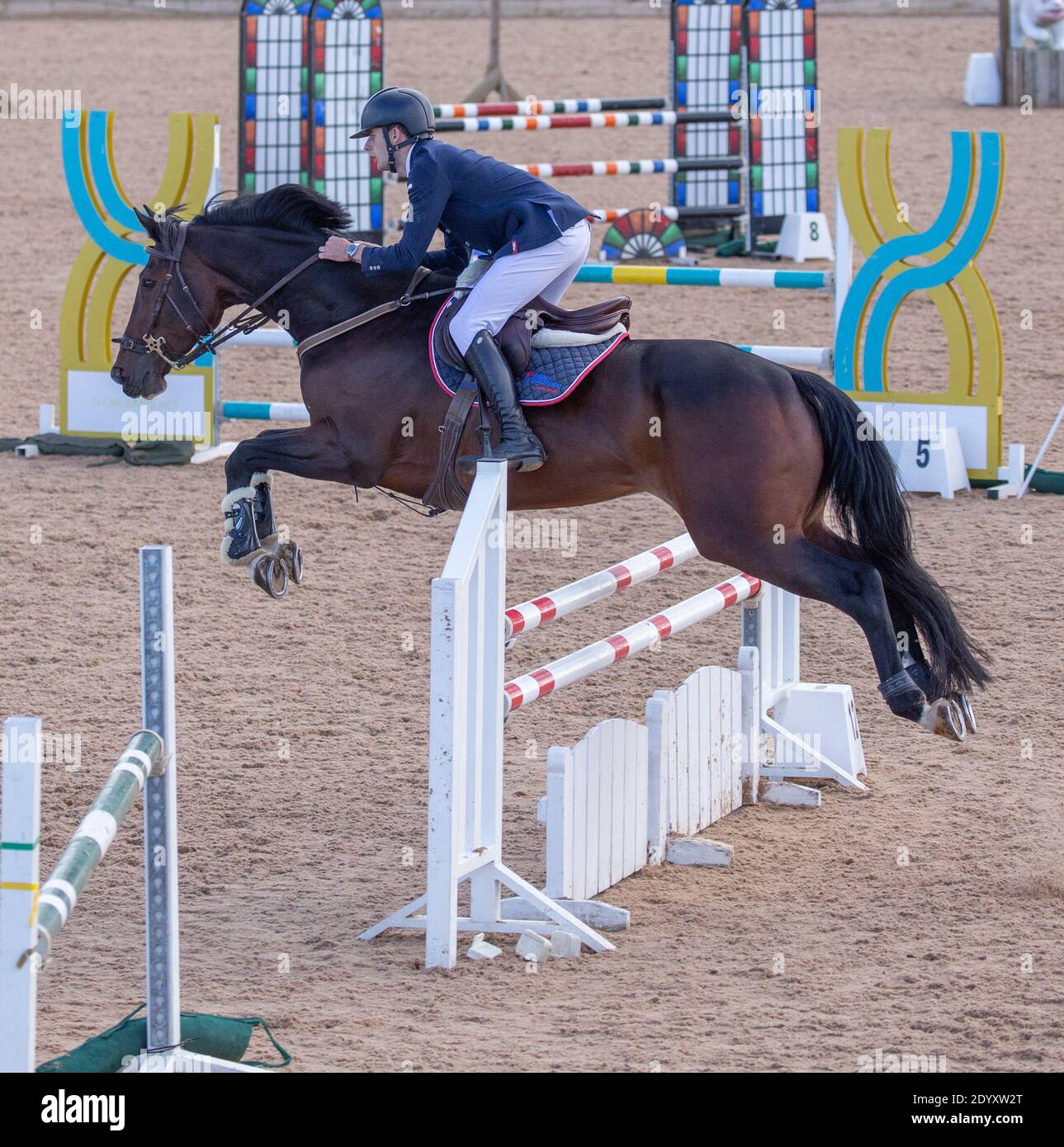 An equestrian rider on their horse jumping over a fence as they take ...