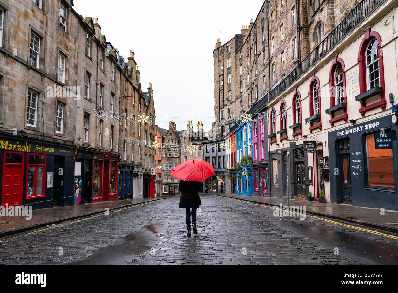 Woman holding red umbrella in rain in Victoria Street in Old Town of Edinburgh, Scotland, UK Stock Photo