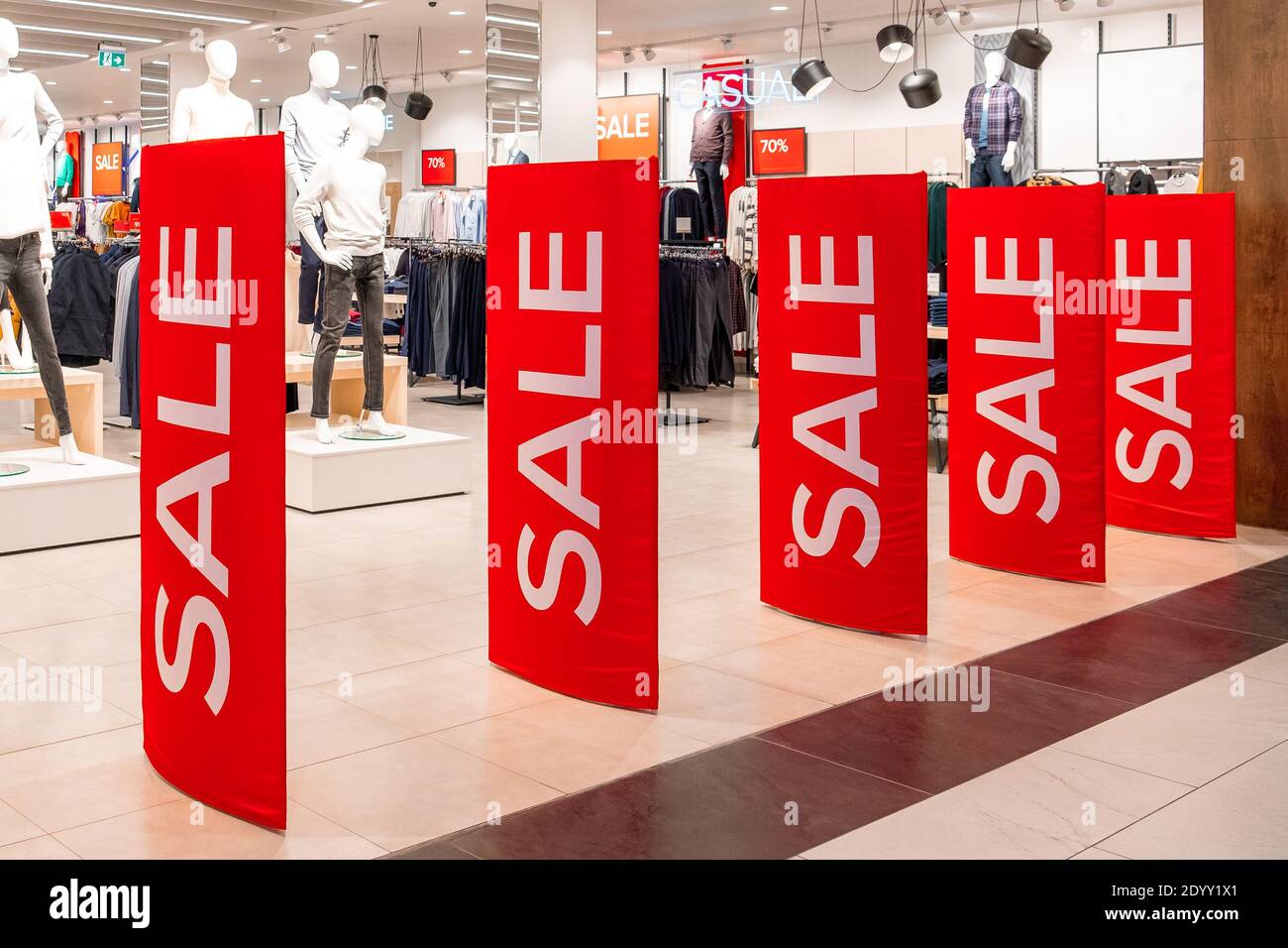 Large red panels with a sale sign at the entrance to a clothing store. On the background are dummy and hangers. Promotion, advertising, shopping and b Stock Photo