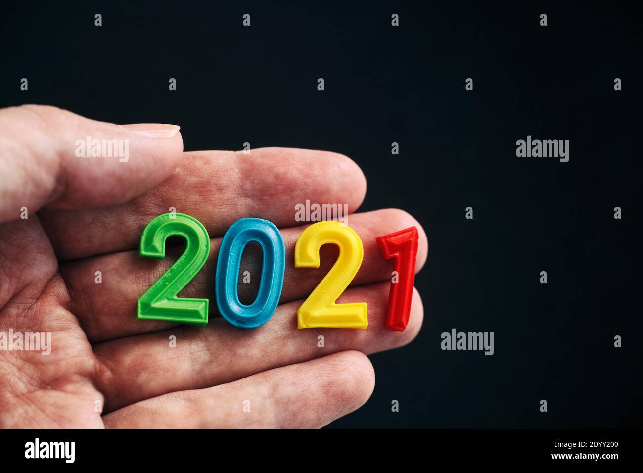 A man holding the year 2021 in his hand. Low key. Stock Photo