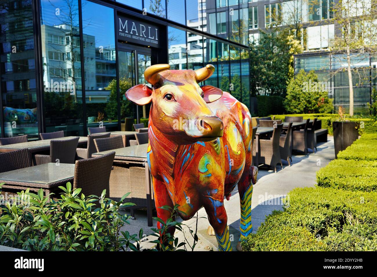 Colourful decorational cow in front of the restaurant „Marli“ in Düsseldorf / Germany, district of Golzheim. Stock Photo