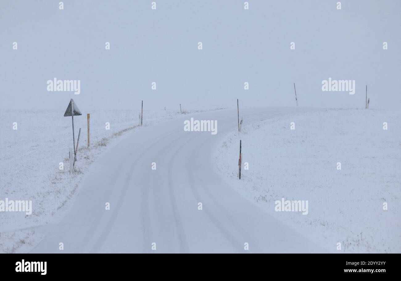 28 December 2020, Bavaria, Stötten: A side road marked with poles runs through the snow-covered Allgäu landscape. Photo: Karl-Josef Hildenbrand/dpa Stock Photo
